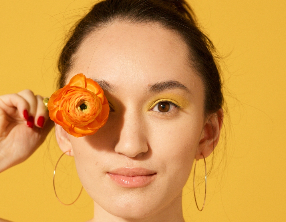 Mujer con flor y agua micelar 